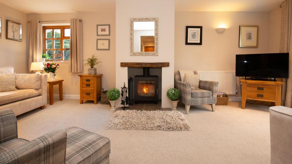 a living room with a fireplace and a tv at Teagles Cottage in Stow, EV parking in Stow on the Wold