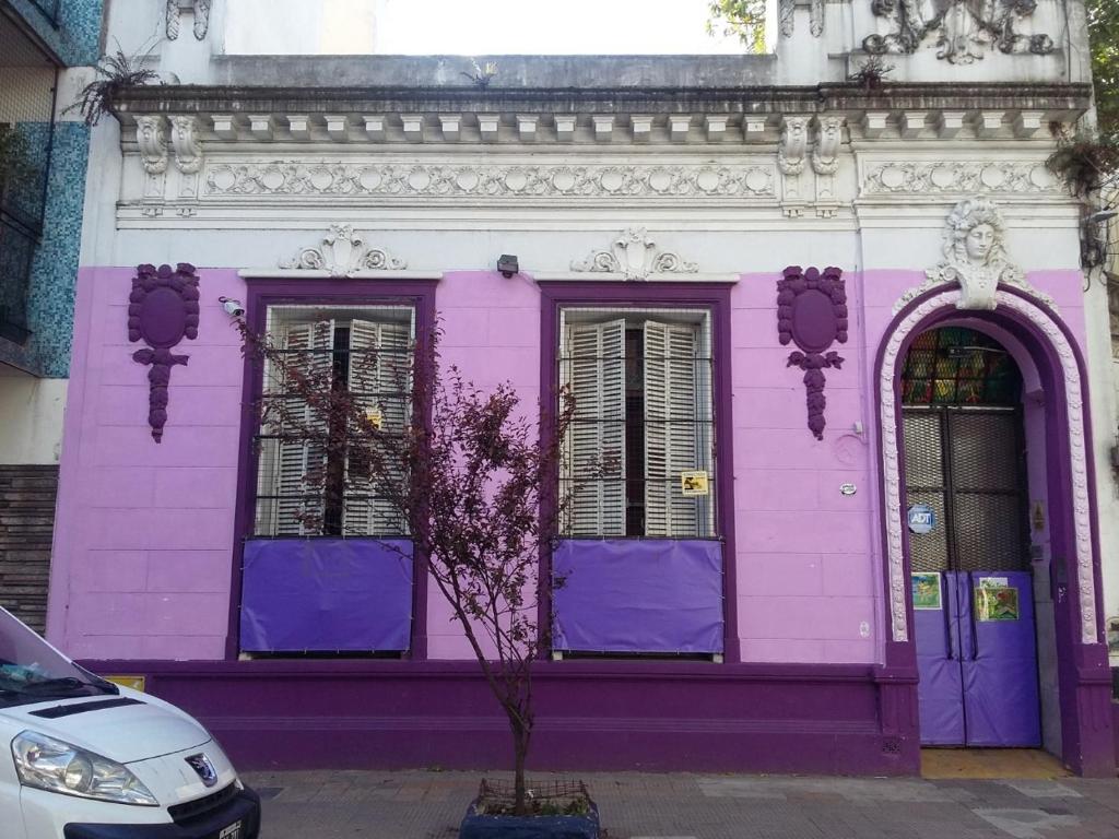 a pink building with purple doors on a street at Hospedaje La Rana in Buenos Aires