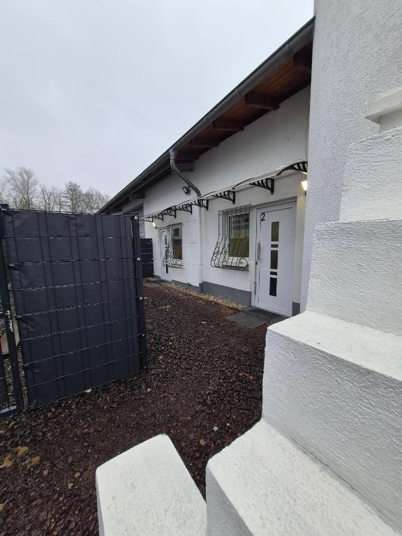 una casa bianca con un cancello nero e un edificio di Cozy 2-bed Room With Kitchen a Rehlingen