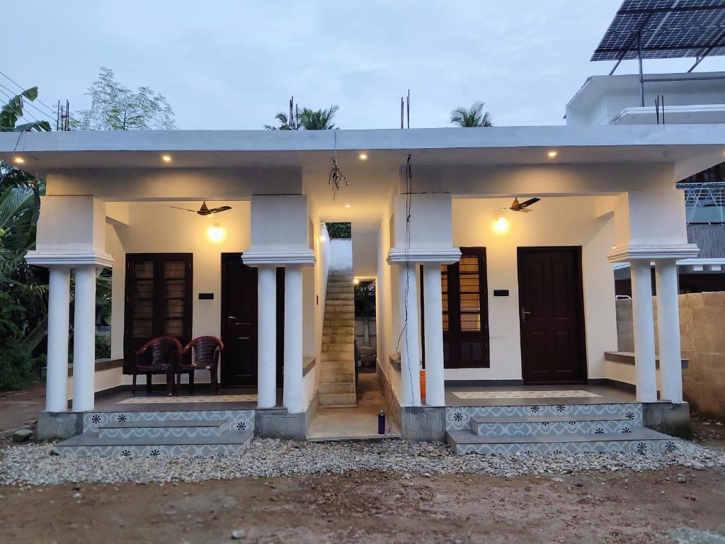 a small white house with columns and a porch at Moonlit Nest in Kappil