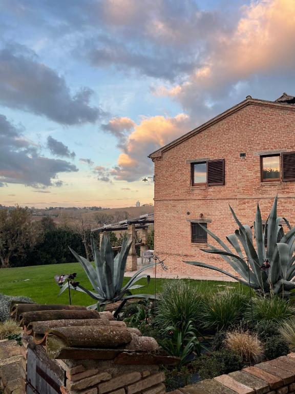a brick house with two large plants in a yard at Villa Altrove in Montemarciano