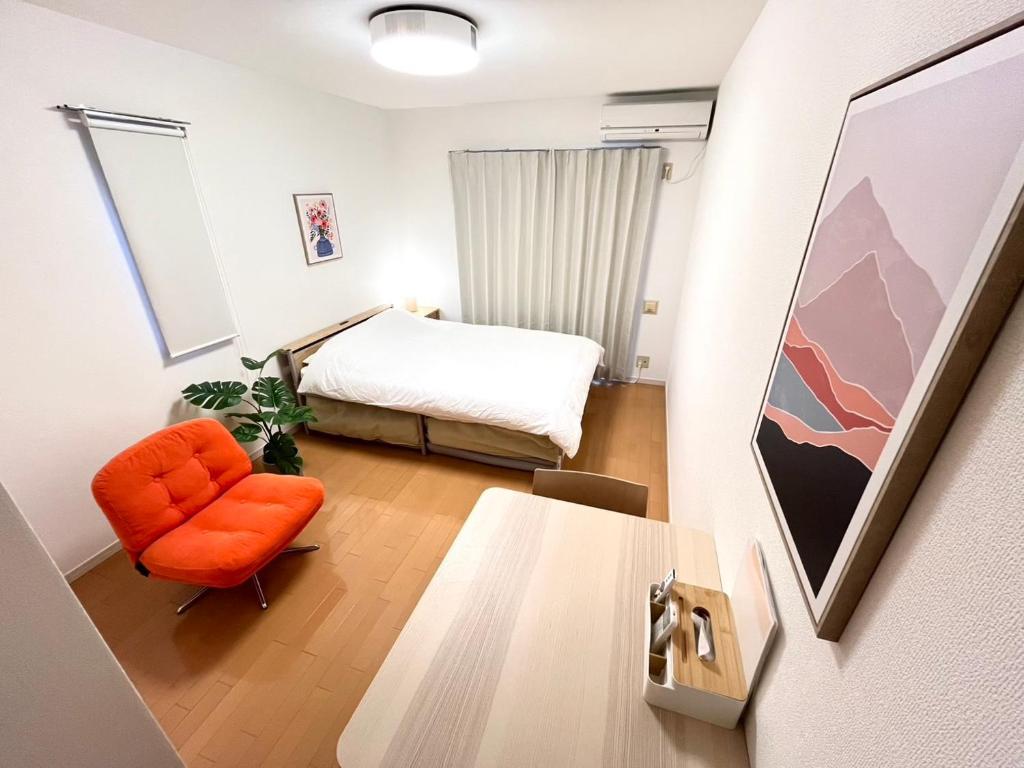 een slaapkamer met een bed en een oranje stoel bij Camelot House 南福岡 in Fukuoka