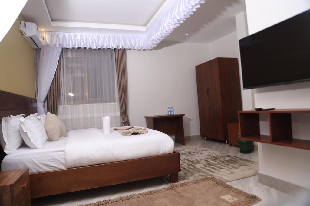 um quarto com uma cama e uma TV de tela plana em DE ALena Villas And Hotel em Mbarara