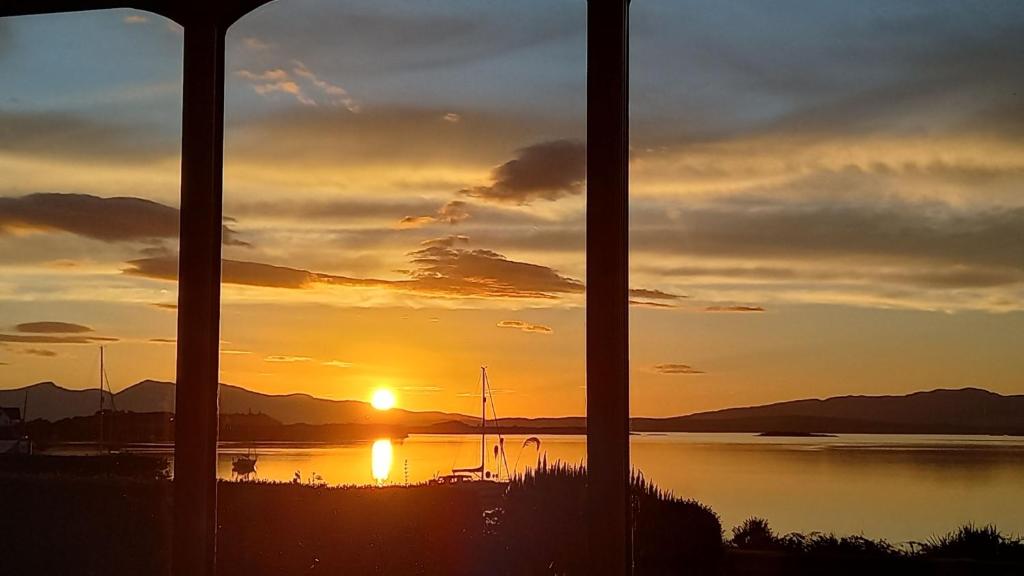 a sunset over a body of water with the sun setting at An Cala in Connel