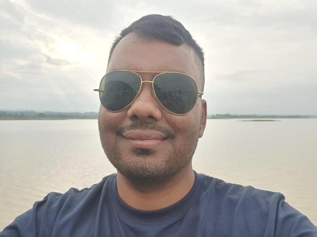 达卡Suite Property Insurance Group Of Company的一名戴着墨镜的男子站在一片水域前