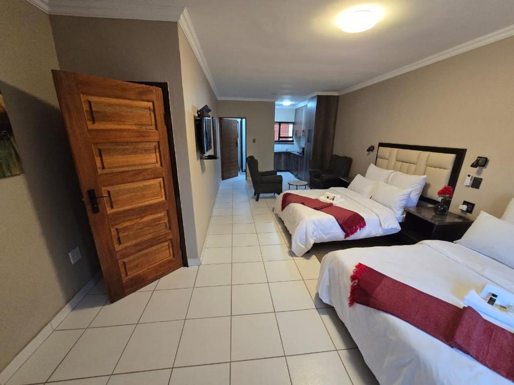 a hotel room with two beds and a door at La Majestic Guest Lodge in Centurion
