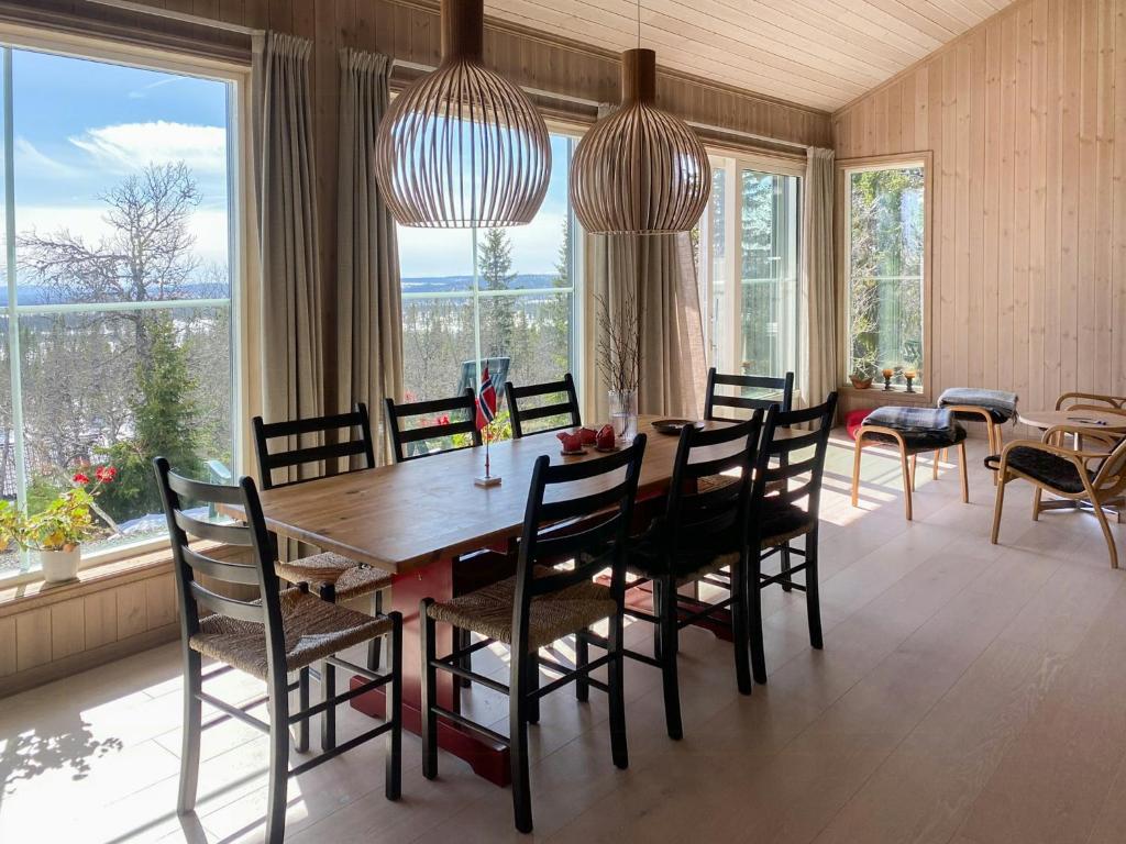 Un comedor con mesa y sillas y ventanas. en New Cabin With Mountain View In Bittermark, Trysil, en Trysil