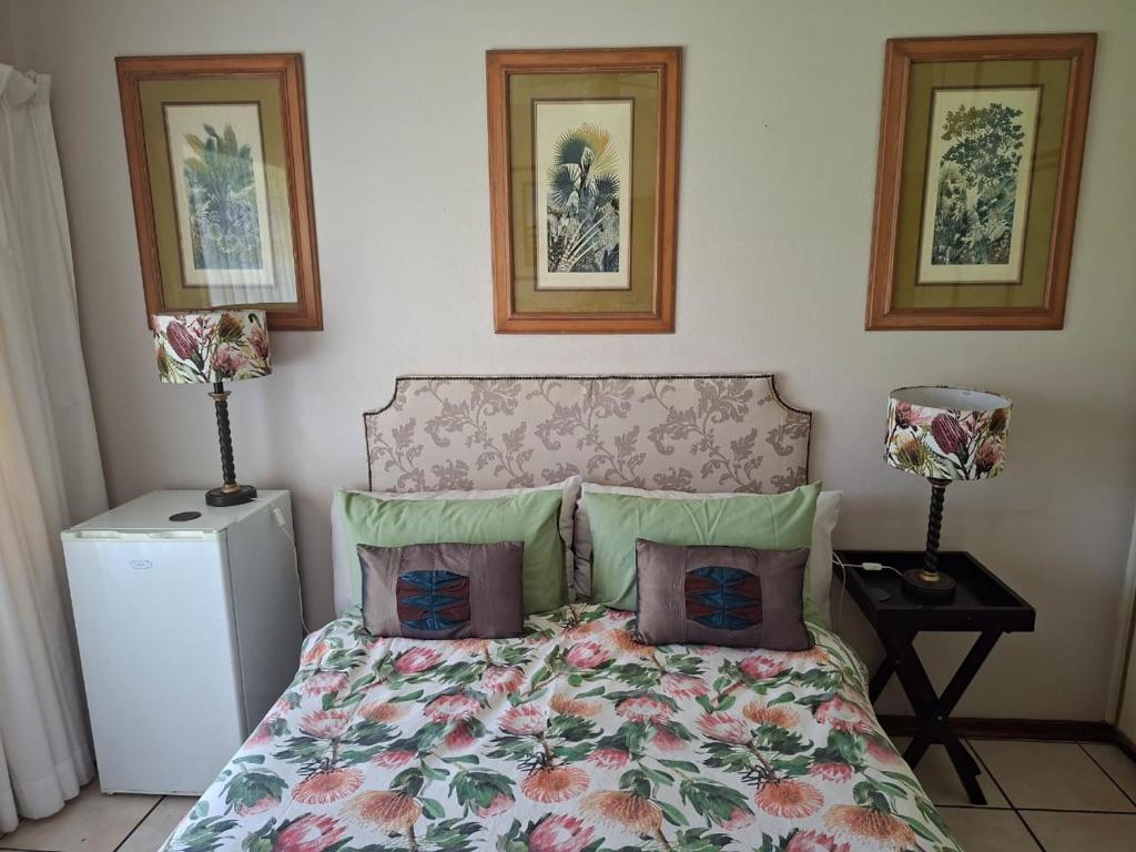 a bedroom with a bed with pillows and a refrigerator at The Manse in Port Shepstone