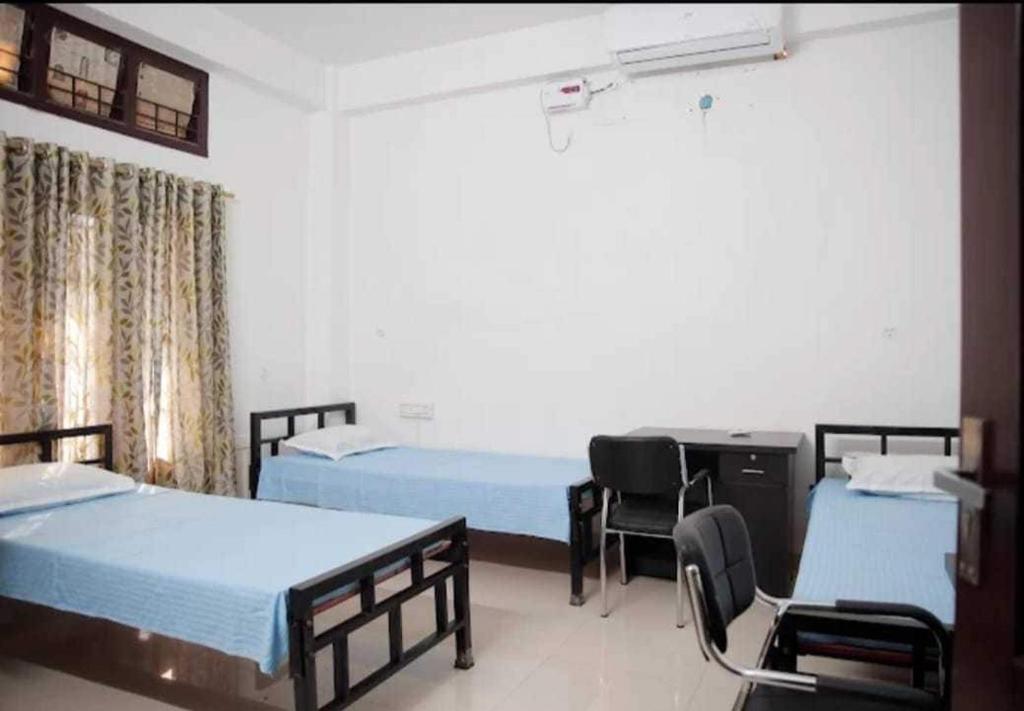 Zimmer mit 3 Betten, einem Schreibtisch und Stühlen in der Unterkunft SPOT ON Sanskrit Guest House in Dispur