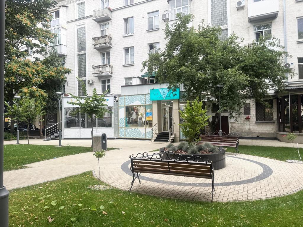 a park with a bench and a tree and a building at Ultra Central Nice Ap in Chişinău