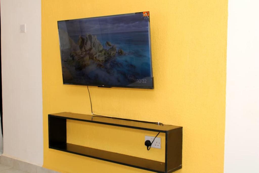 een flatscreen-tv aan een gele muur bij Willary Heights Apartment in Bungoma