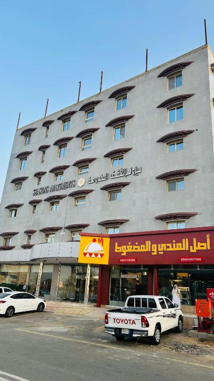 a large building with cars parked in front of it at Seasons Apartments in Jazan