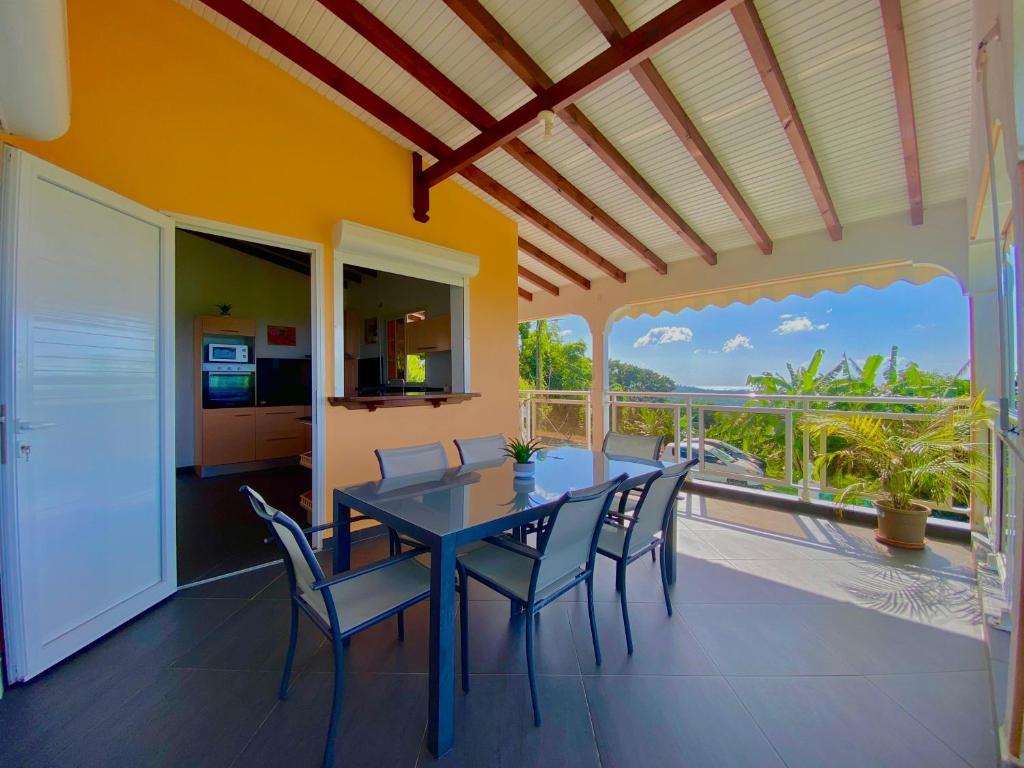a dining room with a table and chairs and a balcony at Villa NKJ'S in Deshaies