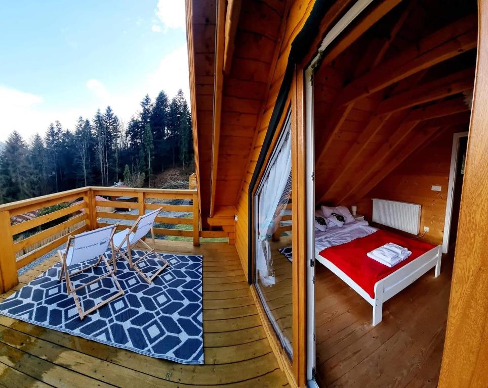 un balcone di una cabina con un letto e delle sedie di Srebrna Polana - sauna, jacuzzi a Międzybrodzie Bialskie