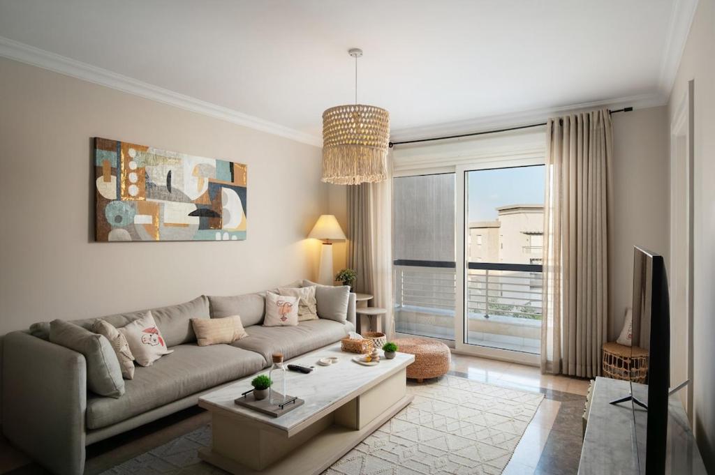 a living room with a couch and a large window at New Giza Boho Bliss in Abū Rawwāsh