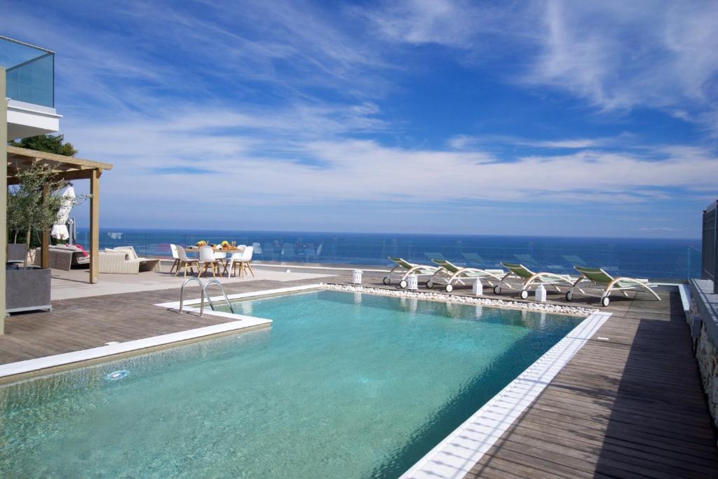 een zwembad met stoelen en de oceaan op de achtergrond bij Villa Ilenia in Skála Kefalonias