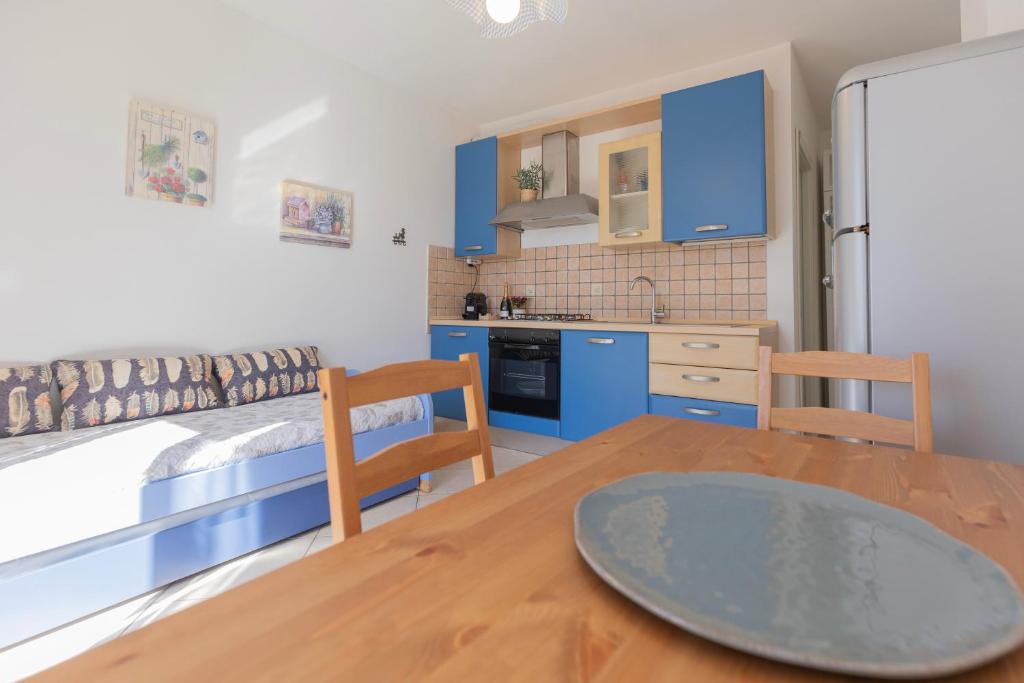 a kitchen and dining room with a table and blue cabinets at Appartamenti La Chiocciola by ElbaSummer in Lacona