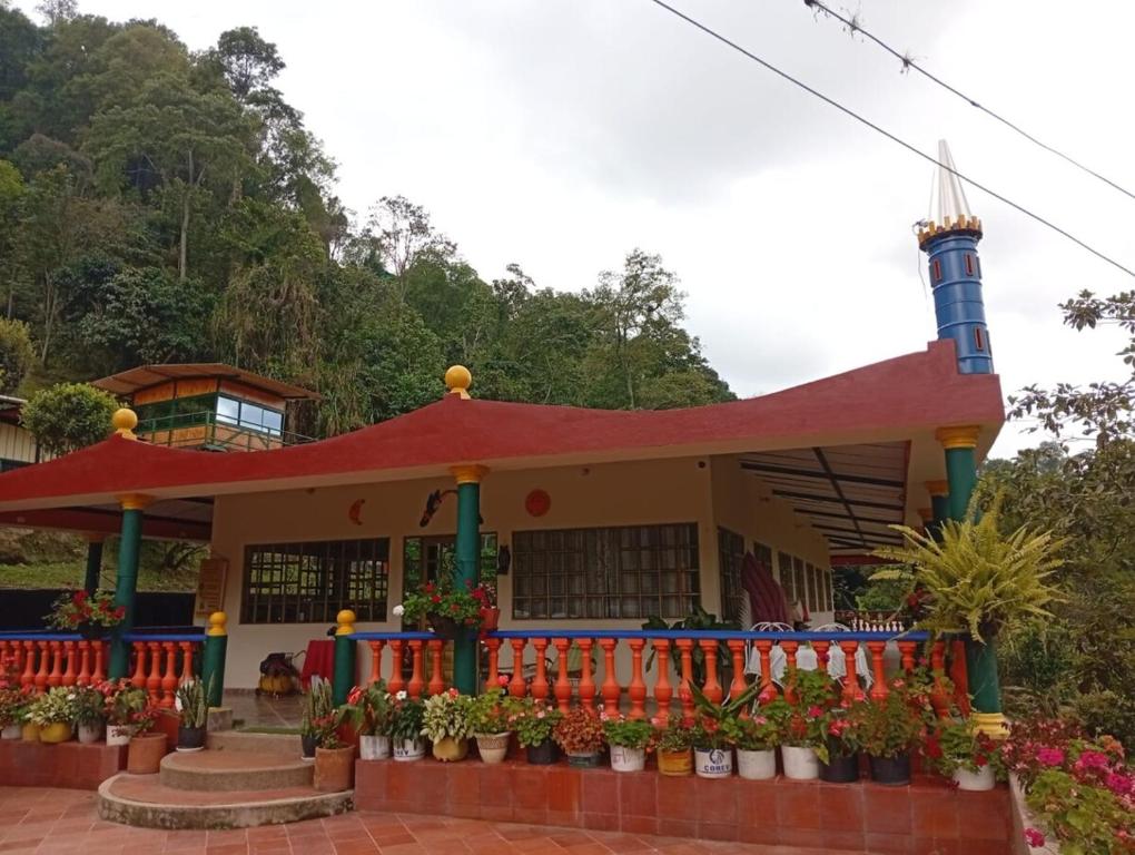 ein Gebäude mit rotem Dach und Blumen in der Unterkunft Mini Apartamento Rural Fusagasuga Finca los Pinos in Fusagasuga