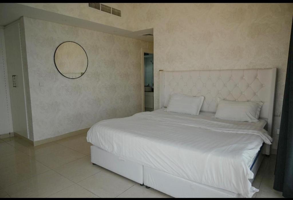 una camera da letto con un letto bianco e uno specchio a parete di شقة في برج داماك a Gedda