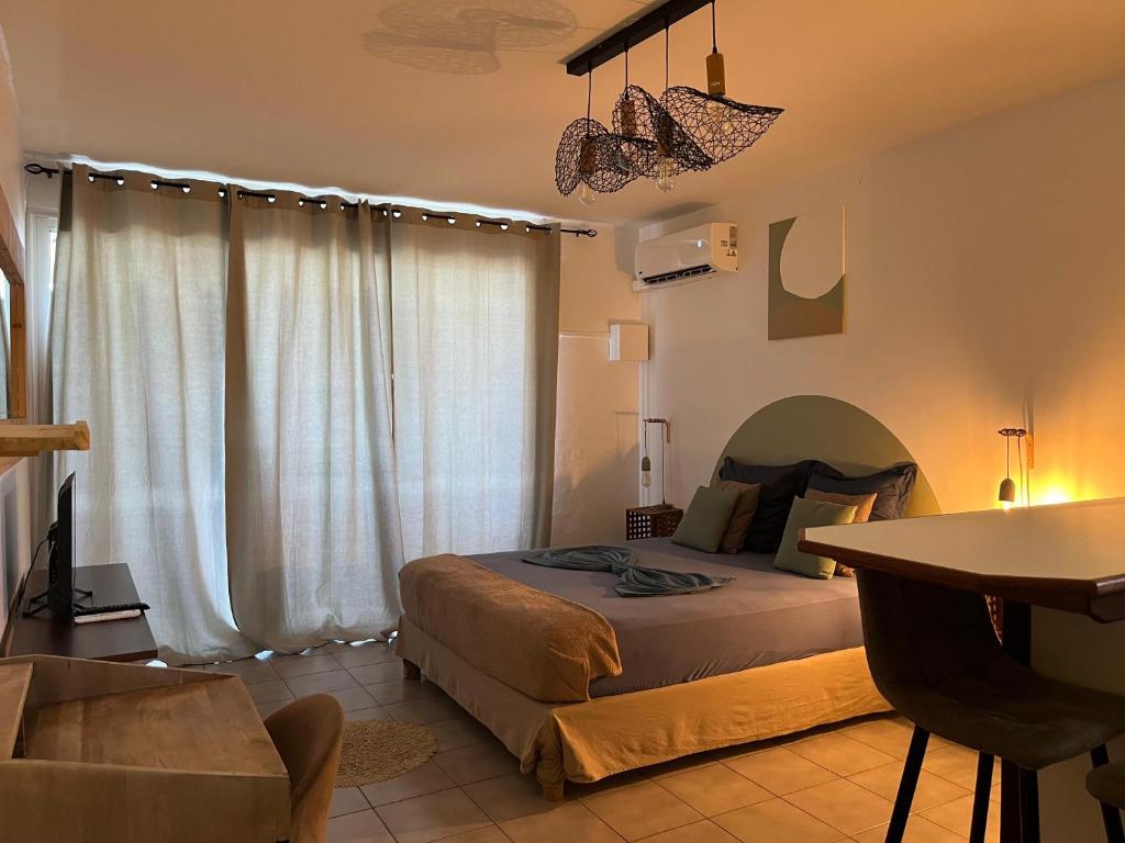 a bedroom with a bed and a table in it at Kaz Mboa Vista - Rémire-Montjoly in Montjoly