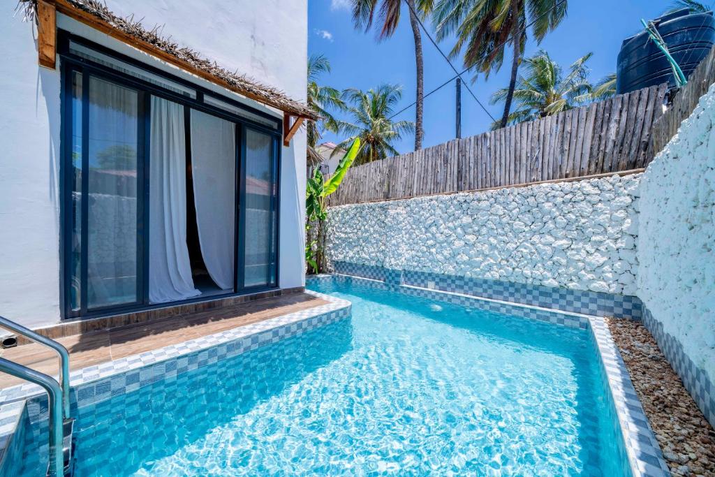 una piscina di fronte a una casa con finestra di Ô TALIA Hôtel and SPA a Nungwi