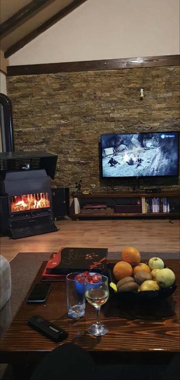 a living room with a table with a bowl of fruit and a fireplace at Svinista vilage in Kičevo