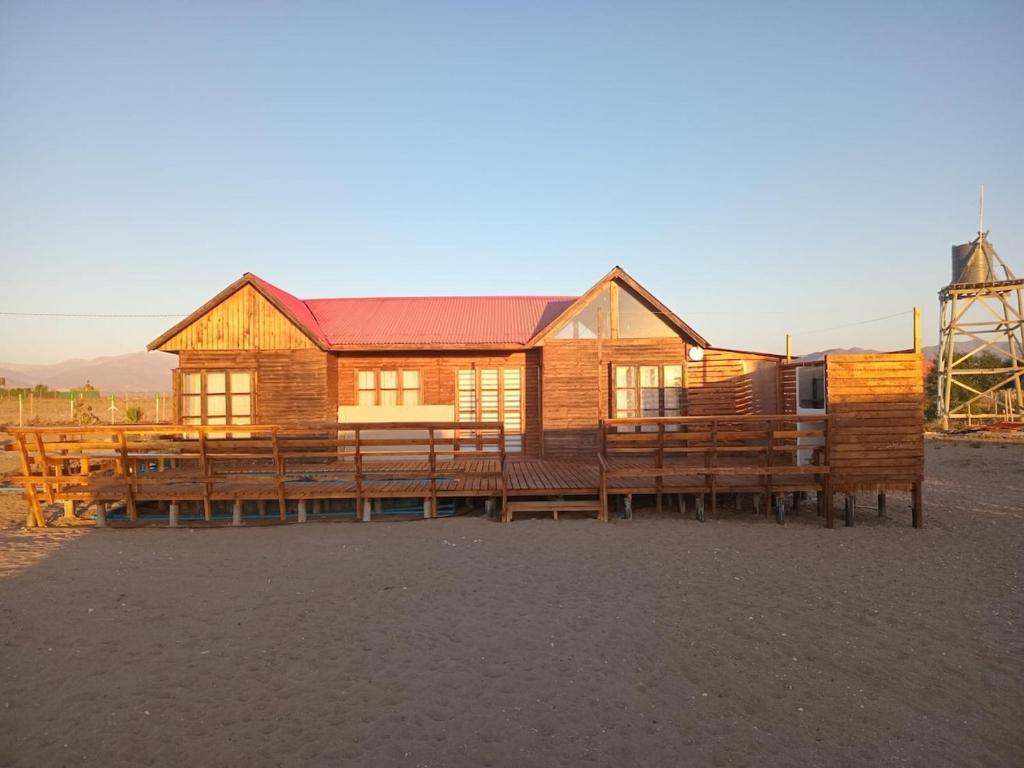 a large wooden house with benches and a windmill at El Fortín de los Choros, un descanso para la familia in Los Choros