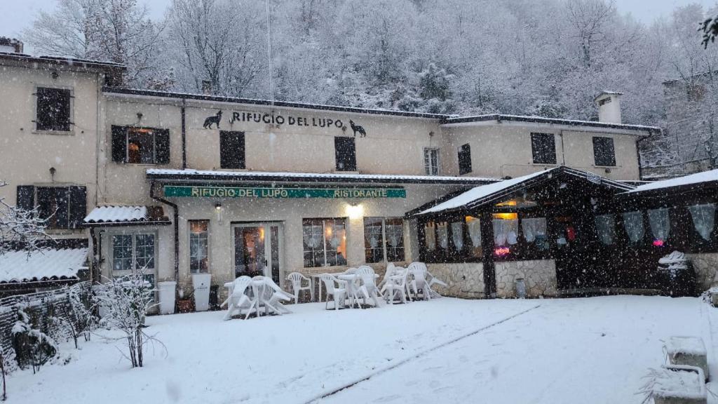 a building with chairs in the snow in front of it at Hotel il Rifugio del Lupo scanno in Scanno