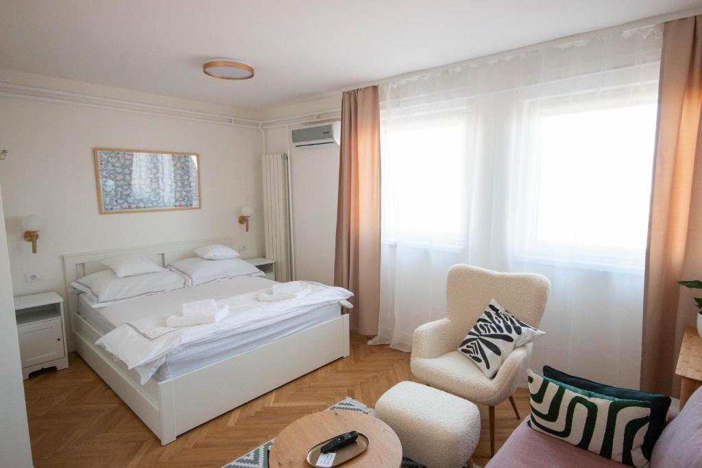 ein weißes Schlafzimmer mit einem Bett und einem Stuhl in der Unterkunft NookLite Studio near Belgrade Arena in Belgrad