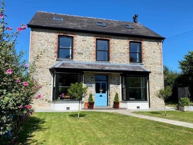 una casa in mattoni con una porta blu in un cortile di Cartrefle - A Charming Welsh Escape perfect for families a St Clears