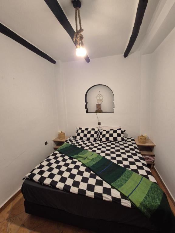 ein Schlafzimmer mit einem schwarz-weiß karierten Bett in der Unterkunft Le Riad Bed & Breakfast in Agadir