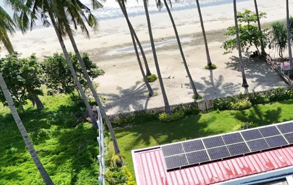 PRIVATE VILLA FRONT BEACH Infinity Pool في سان فيسنتي: منظر علوي لشاطئ به أشجار نخيل وألواح شمسية