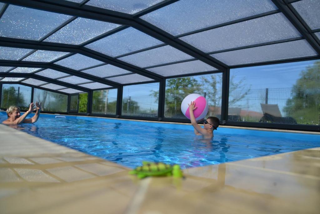 zwei Kinder spielen mit einem Strandball im Pool in der Unterkunft Gîte de la loge SAMY in Châtillon-sur-Broué