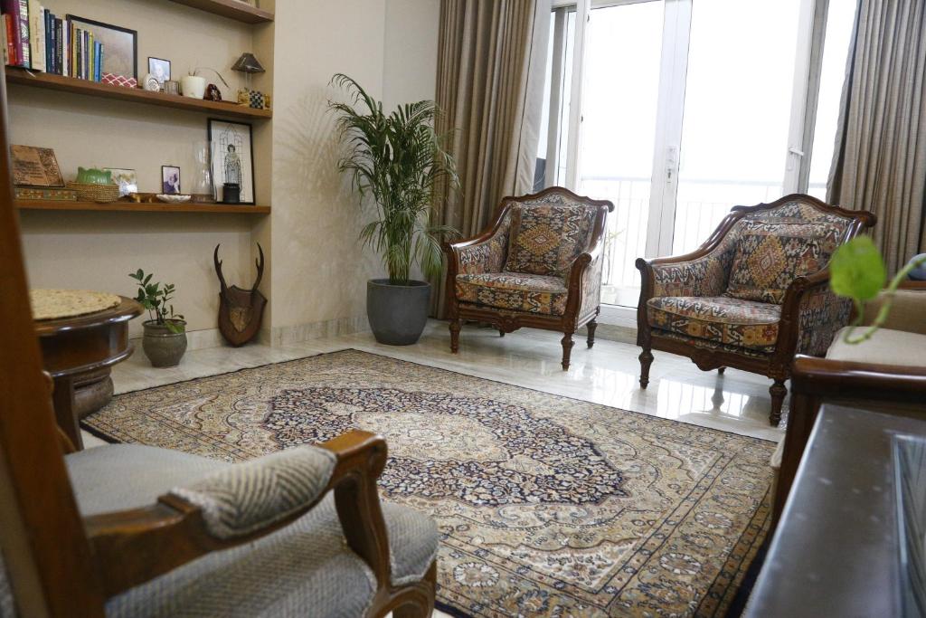 a living room with two chairs and a rug at Entire Vintage Apartment, Historic Heights Haven in Noida