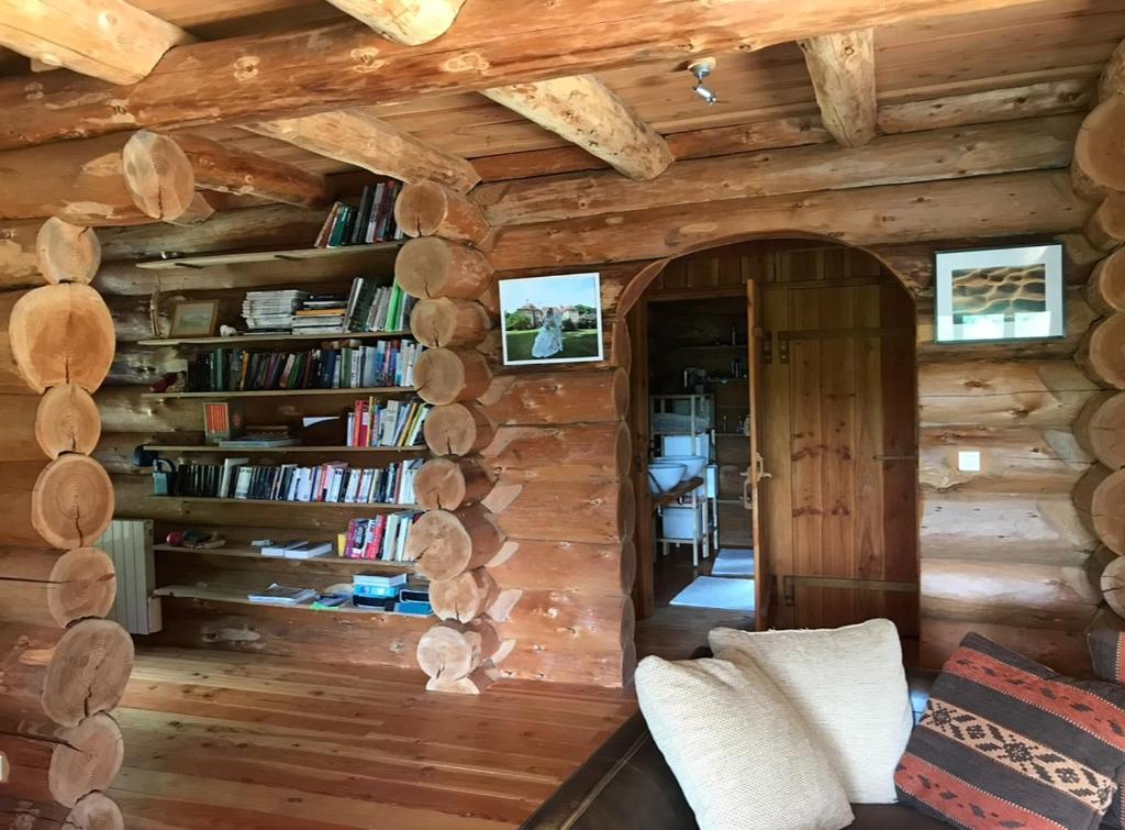 Una sala de estar con una pared de troncos con estanterías. en Chalet canadien en Morvan, en Rouvray