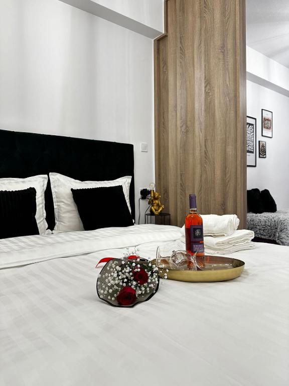 a white bed with a bottle of alcohol and a tray on it at Panthera-urban-studio in Xanthi