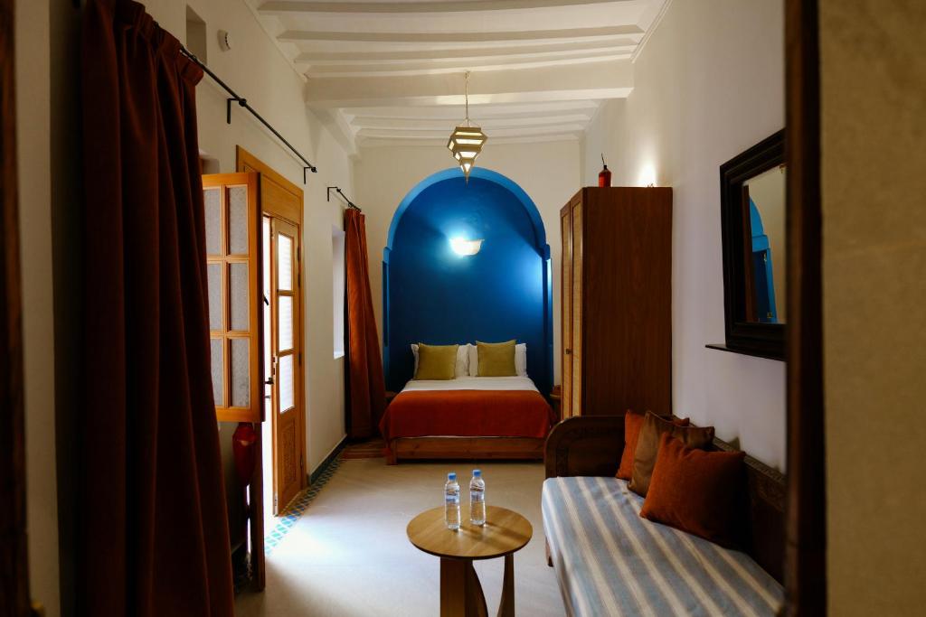 索维拉Riad Mazal Mogador的房间里有一张沙发和一张床，墙壁是蓝色的。