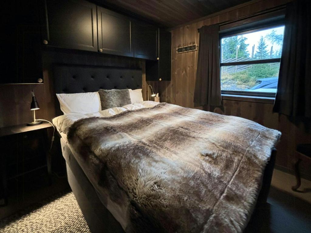 Un dormitorio con una cama grande con ventana. en Modern Cabin With Views Of Skeikampen, en Svingvoll