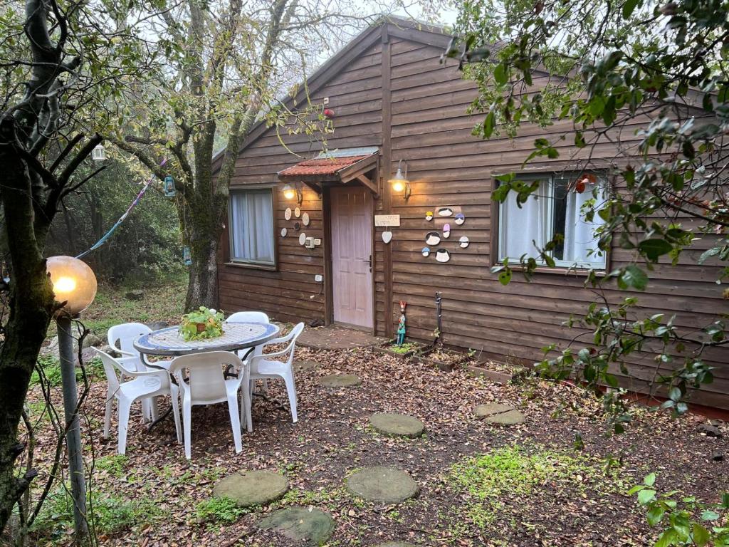 einen Tisch und Stühle vor einer Hütte in der Unterkunft בקתת היערן- בטבע פראי למשפחות ולזוגות in Merom Golan