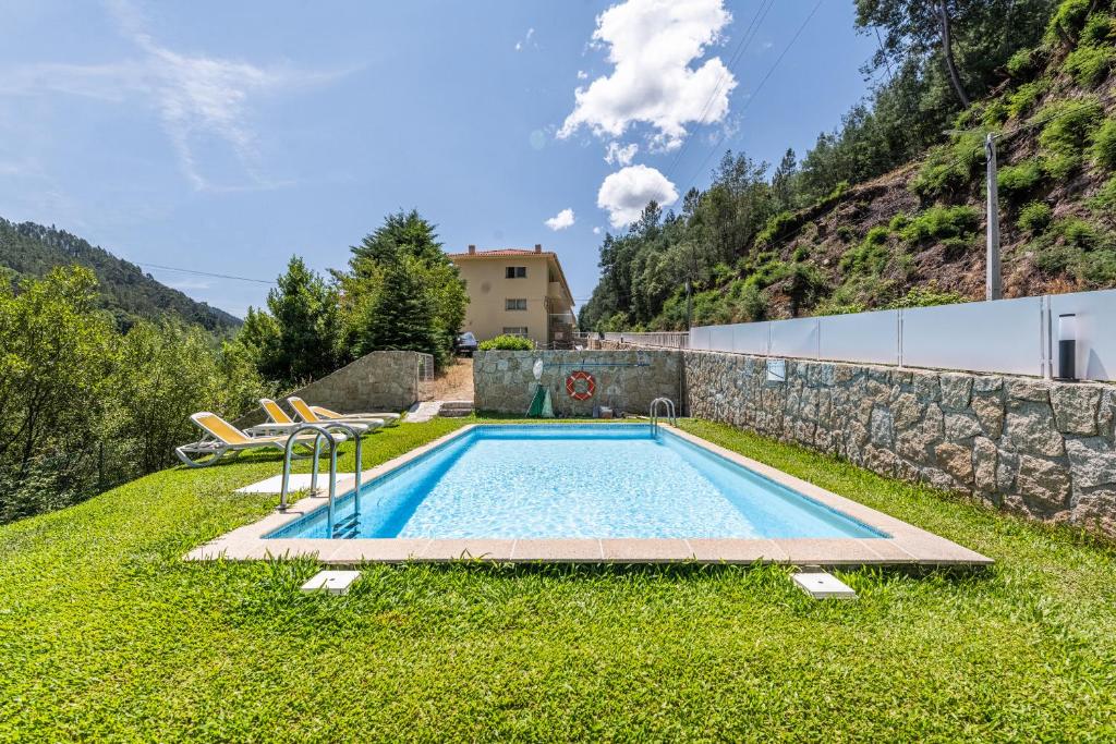 a swimming pool in the yard of a house with a mountain at Gerês Cascatas Residence in Geres