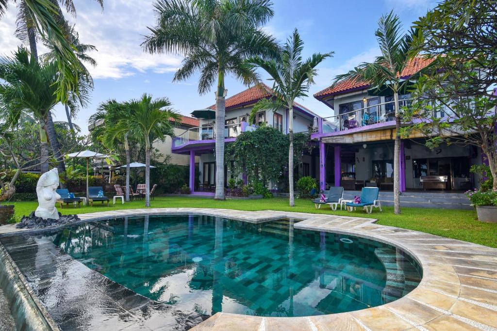 a swimming pool in front of a house with palm trees at Dolphin Beach Bali in Lovina