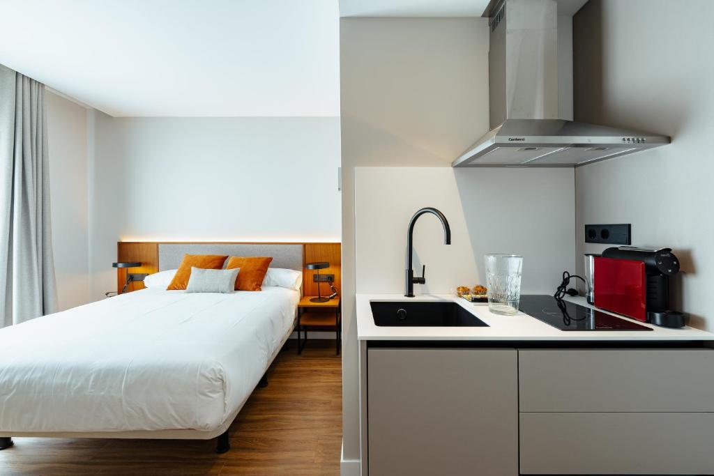 Un dormitorio con una cama y una cocina con fregadero. en Apartamentos 2H LIVING, en León