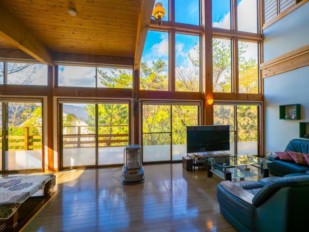 a living room with a large room with windows at Beautiful Nasu, the center of Nasu, Up to 12 people, 3 bedrooms, BBQ on the deck, night karaoke in Nasu