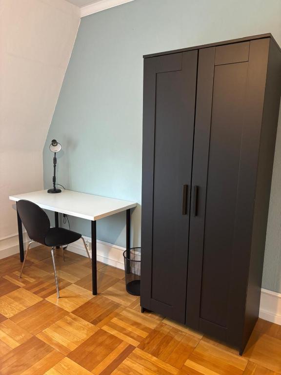 a black cabinet next to a desk and a table at private Zimmer im Serviced Apartment - mit wöchentlicher Reinigung in Stuttgart