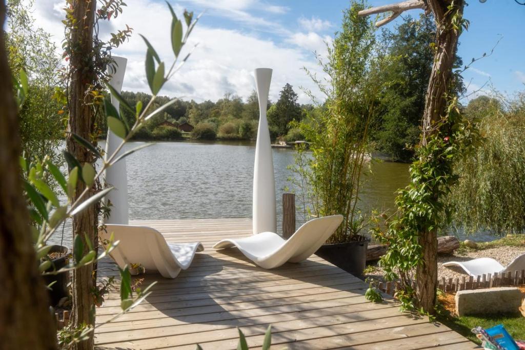 a wooden deck with white chairs and a lake at Cottage, Lodge & Spa 54 in Prouilly