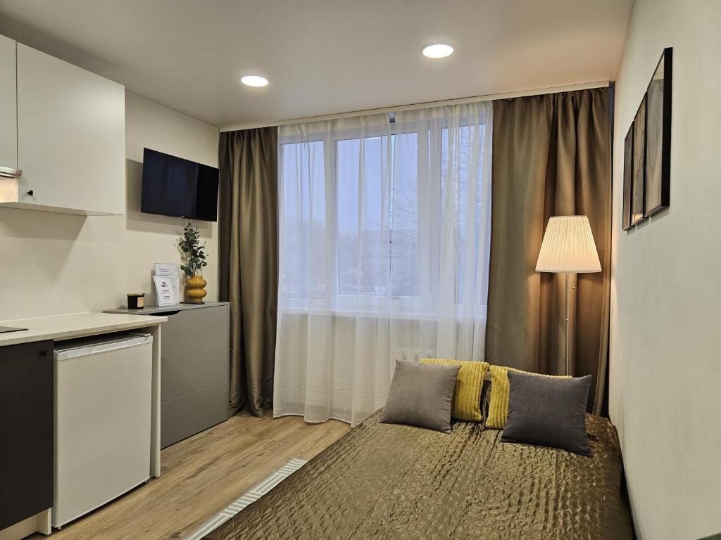 un soggiorno con letto e una grande finestra di Airport & Station Stay Vilnius a VNO
