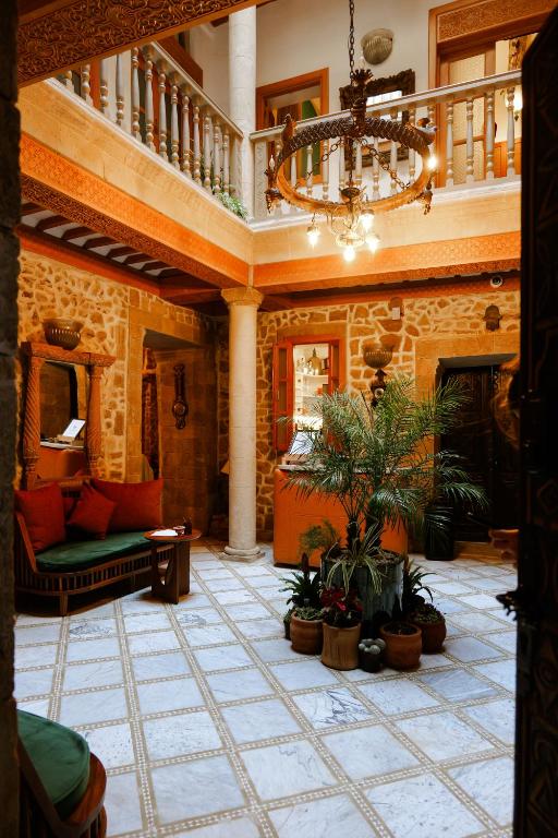 a living room with a chandelier and plants on the floor at Riad Mazal Mogador in Essaouira