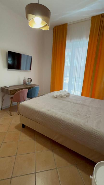 een slaapkamer met een bed, een bureau en een televisie bij Le Corti del Re Tappia in Napels