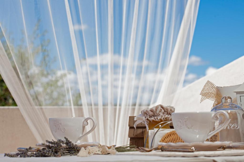 una mesa con dos tazas de té y una ventana en La Pulcia B&B, en Gradara