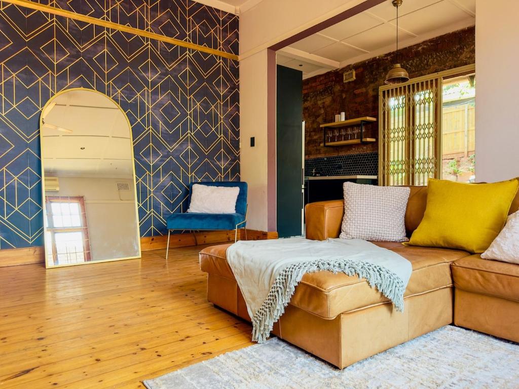 LadyBird Cottage في ديربان: غرفة معيشة مع أريكة وكرسي